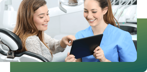 Dentist showing a patient information on a tablet during a routine dental check-up.