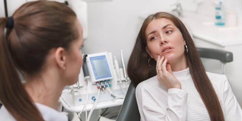 A woman with a toothache seeks emergency dental care from her dentist.