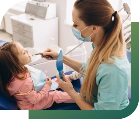 A female dentist gently examines a young child's teeth in a dental clinic.