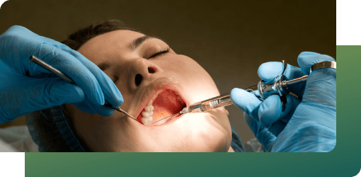 Dentist injecting anesthesia into a patient's open mouth with dental tools for a wisdom tooth removal procedure.