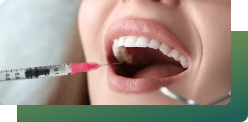 Close-up of a dentist using a syringe to give local anesthesia inside a patient's mouth during a tooth filling procedure.