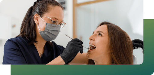 A cosmetic dentist using a tool to examine a patient's teeth and identify issues that may impact the smile makeover treatment plan.