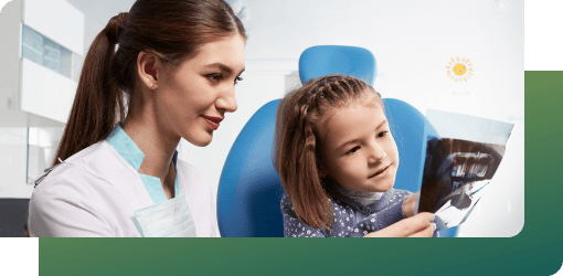 Dentist reviewing X-ray with a young girl to evaluate her pediatric orthodontics needs using digital imaging in a clinic.