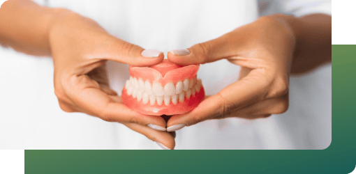 Hands hold a dental model, representing custom dentures in general dental services for restoring facial aesthetics and function.