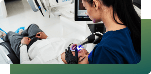 A dentist performs a procedure on a patient, utilizing CEREC technology to take digital impressions and create a precise virtual model of the teeth for inlays and onlays.