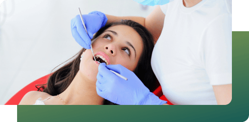 Dentist examining the damage to the teeth in the lower jaw of a patient, using dental tools.