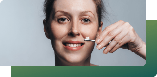 Smiling woman applying a small strip to her nose, using personalized tips from the dental crown procedure for long-lasting results.