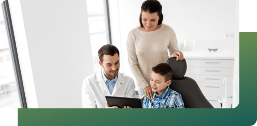 An emergency pediatric dentist giving oral hygiene tips to a young boy and his mother at a dental clinic.