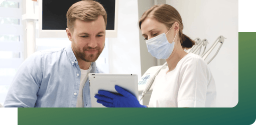 A dentist and patient review a tablet to plan a full smile makeover, ensuring desired outcomes and answering questions.