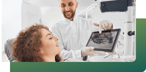 A dentist explaining a patient's teeth X-ray during a procedure.